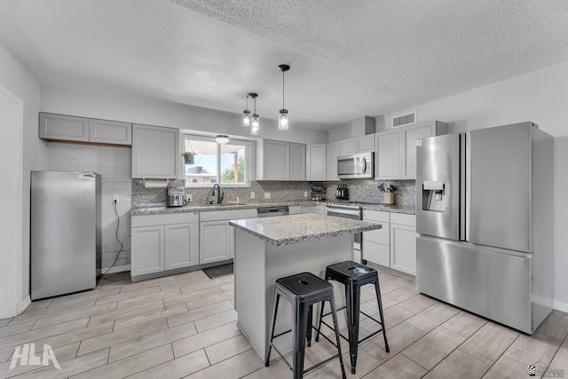 kitchen with stainless steel appliances, backsplash, a sink, and wood tiled floor