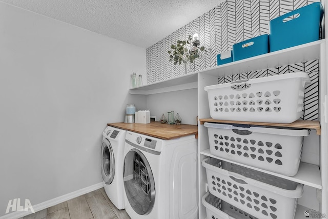 clothes washing area featuring laundry area, baseboards, a textured ceiling, wood finish floors, and washing machine and dryer