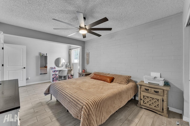 bedroom featuring a ceiling fan, wood finish floors, a textured ceiling, and baseboards