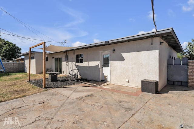 rear view of property featuring a trampoline, a patio area, fence, and stucco siding