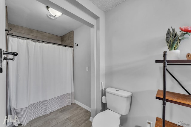 bathroom with baseboards, wood finished floors, toilet, and a shower with curtain