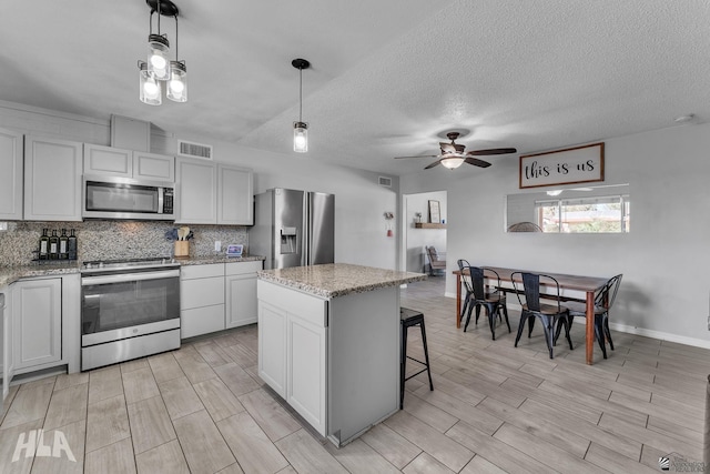 kitchen featuring visible vents, decorative backsplash, appliances with stainless steel finishes, wood tiled floor, and a kitchen island