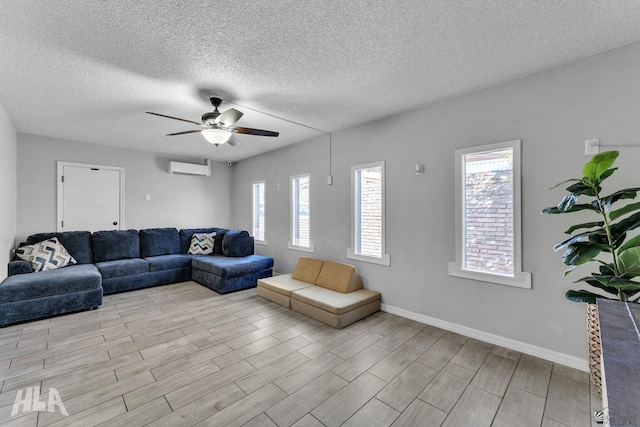 living room featuring a textured ceiling, light wood-style flooring, a ceiling fan, baseboards, and an AC wall unit