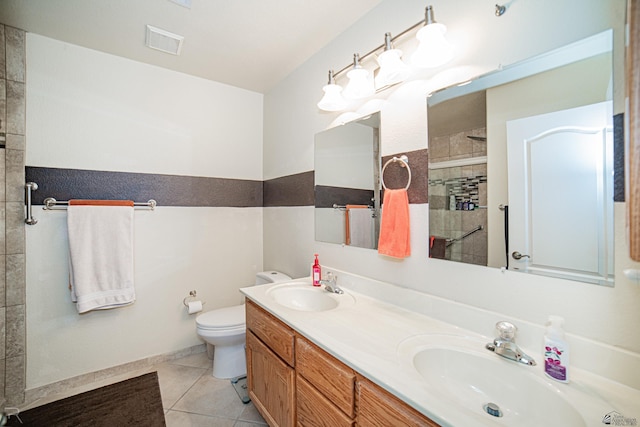 bathroom with toilet, a tile shower, vanity, and tile patterned floors