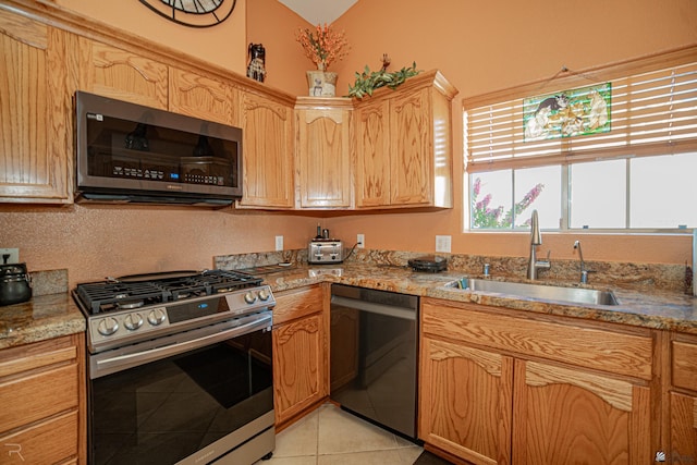 kitchen featuring light stone counters, stainless steel appliances, vaulted ceiling, sink, and light tile patterned floors