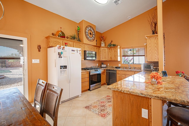 kitchen with sink, vaulted ceiling, light tile patterned floors, light stone countertops, and appliances with stainless steel finishes