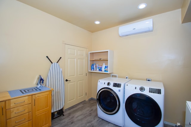 laundry area with washing machine and dryer, a wall mounted AC, and light hardwood / wood-style flooring