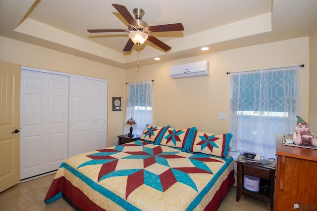 bedroom featuring ceiling fan, a tray ceiling, a closet, and a wall mounted AC