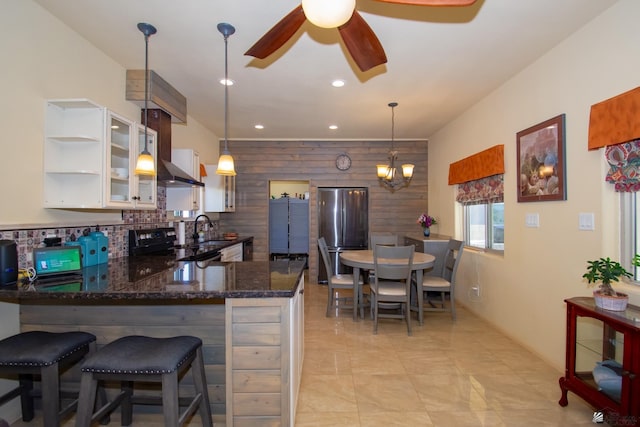 kitchen featuring wood walls, decorative light fixtures, stainless steel refrigerator, kitchen peninsula, and white cabinets