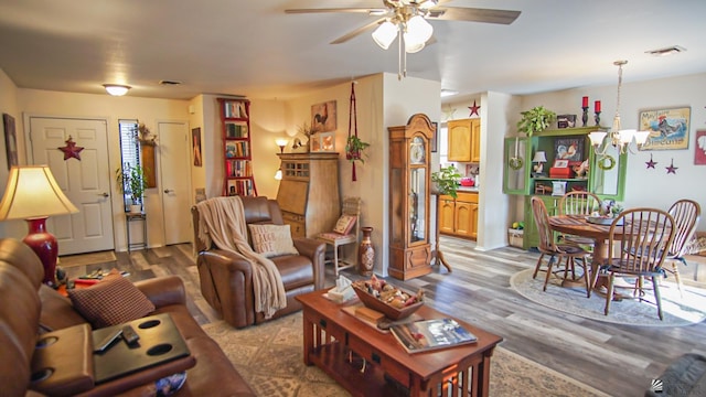 living room featuring ceiling fan with notable chandelier and light wood-type flooring