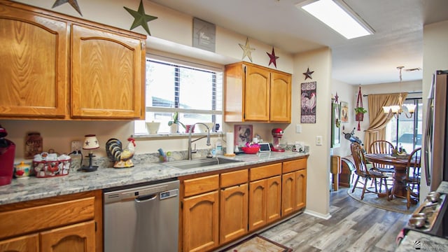 kitchen with dishwasher, sink, light hardwood / wood-style flooring, a chandelier, and decorative light fixtures