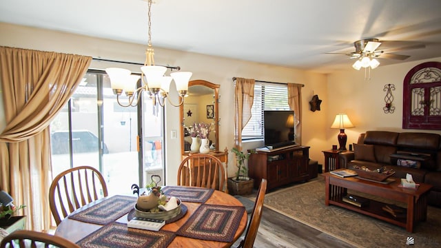 dining area featuring ceiling fan with notable chandelier and dark wood-type flooring