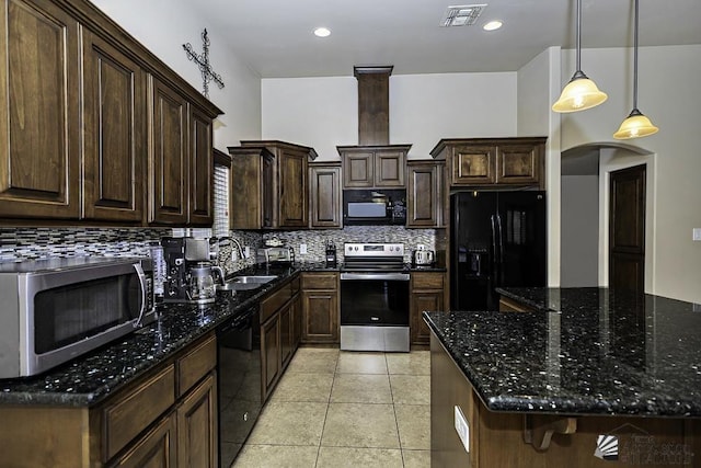 kitchen featuring sink, dark stone counters, decorative light fixtures, a kitchen island, and black appliances