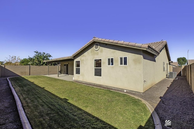 rear view of property with a yard, cooling unit, and a patio