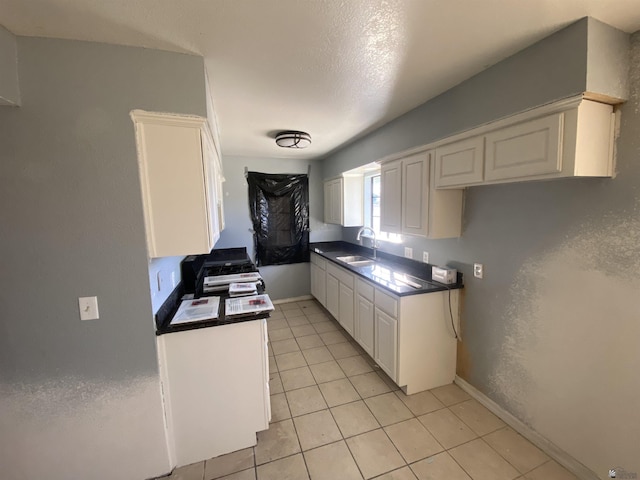 kitchen featuring light tile patterned flooring, white cabinetry, sink, and white range with gas stovetop