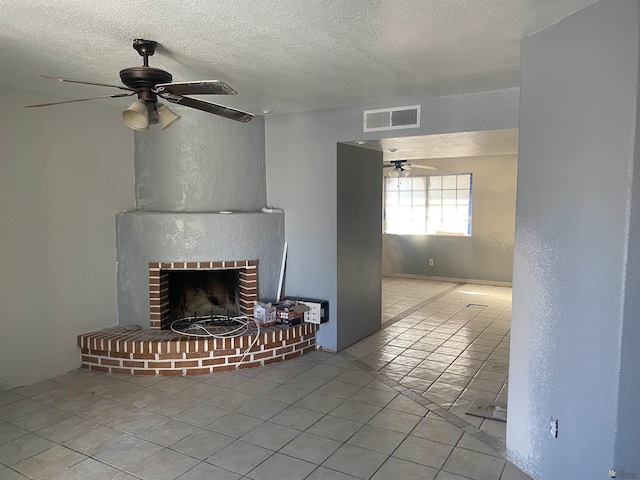 unfurnished living room featuring ceiling fan, a textured ceiling, and a brick fireplace