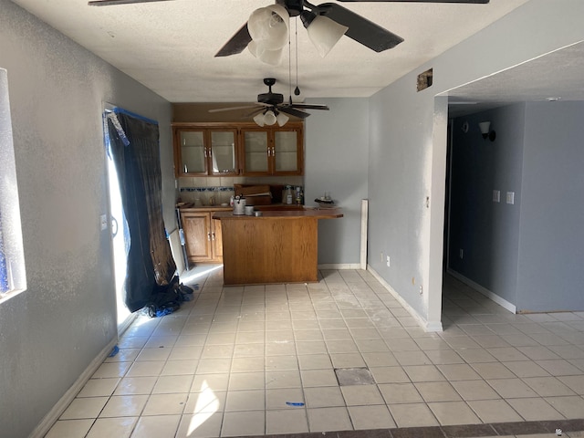 kitchen featuring kitchen peninsula, light tile patterned floors, and backsplash