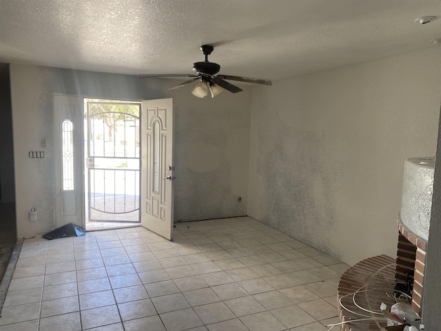 tiled entrance foyer with a textured ceiling and ceiling fan