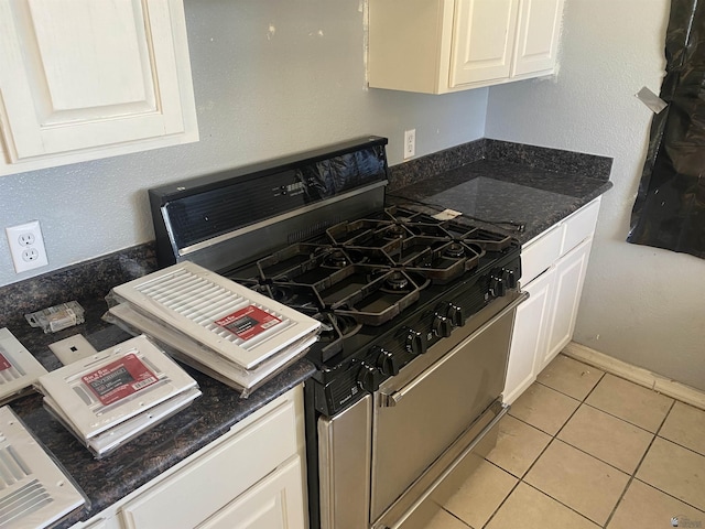 kitchen with white cabinetry, dark stone countertops, light tile patterned floors, and stainless steel gas range