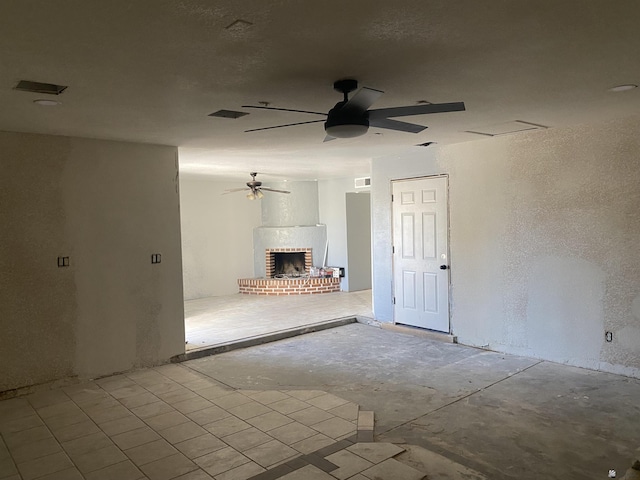 unfurnished living room featuring a brick fireplace and ceiling fan