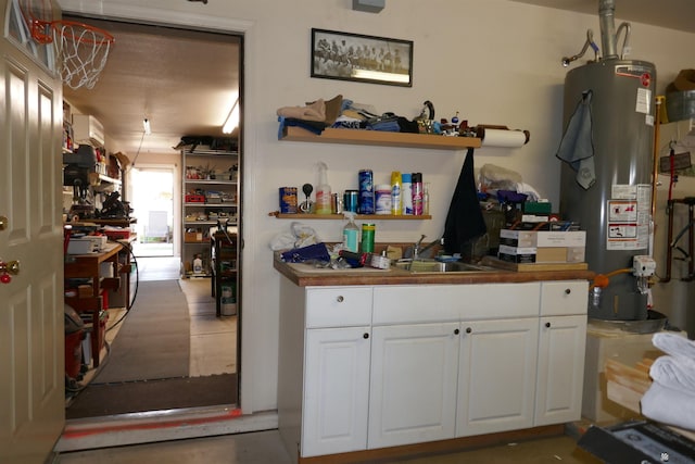 kitchen with gas water heater, white cabinetry, and sink