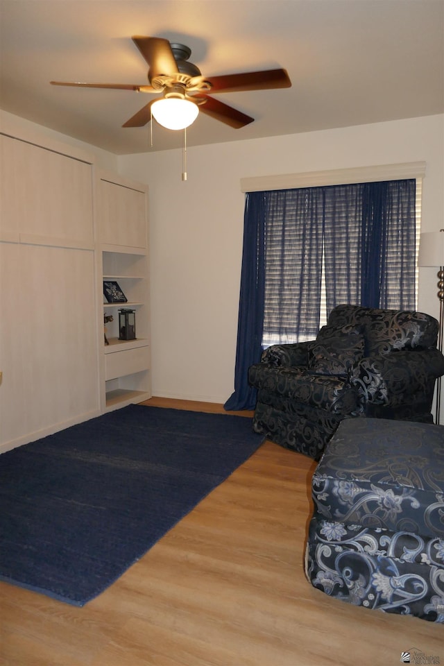 unfurnished living room with ceiling fan, wood-type flooring, and built in shelves