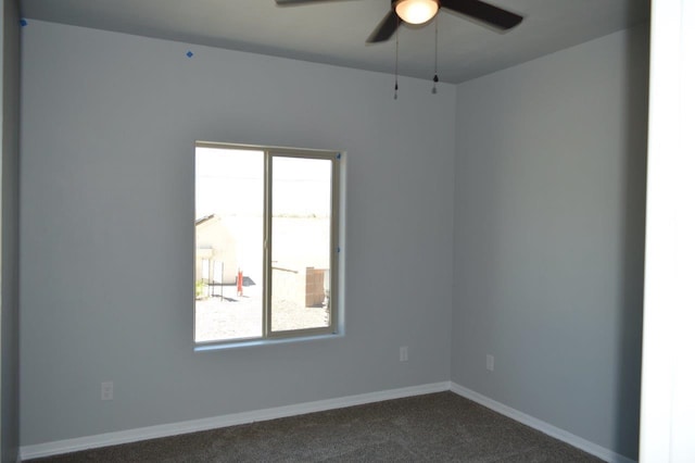 spare room featuring dark colored carpet, a wealth of natural light, and ceiling fan