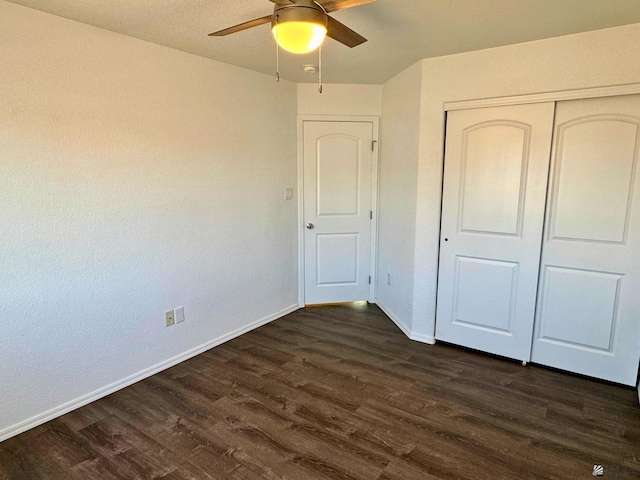 unfurnished bedroom with ceiling fan, dark wood-type flooring, and a closet