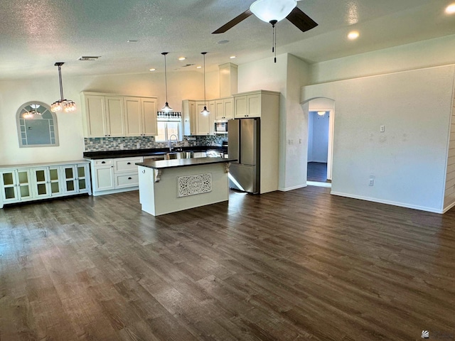 kitchen with backsplash, stainless steel appliances, white cabinets, a kitchen island, and hanging light fixtures