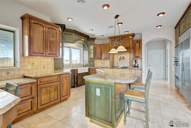 kitchen with a breakfast bar, decorative light fixtures, a kitchen island, and tasteful backsplash