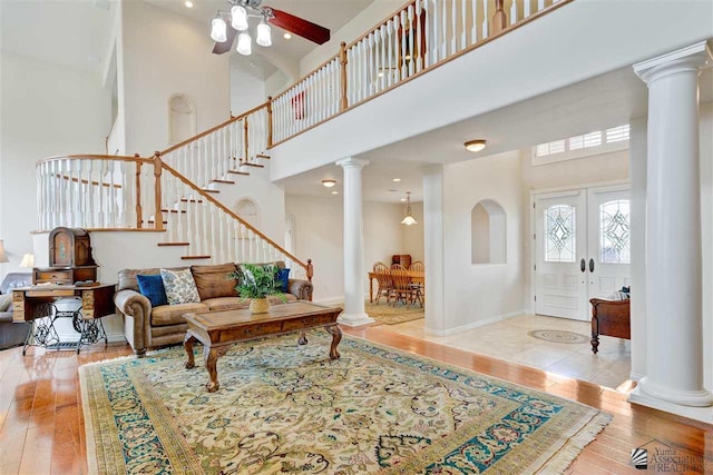 living room with ceiling fan, french doors, a towering ceiling, and wood-type flooring