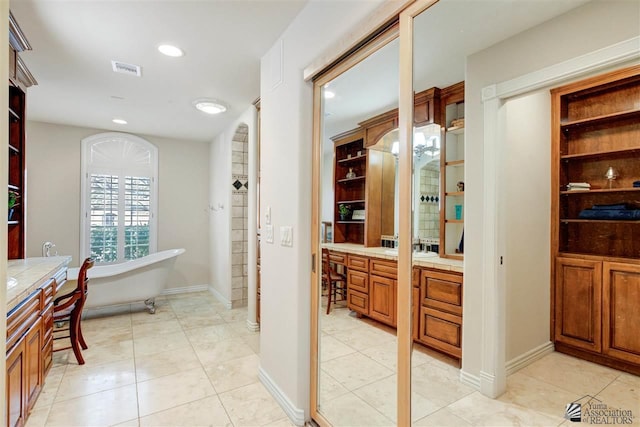 bathroom featuring vanity, tile patterned floors, and a tub