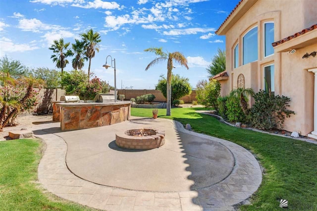 view of patio / terrace with exterior kitchen and an outdoor fire pit