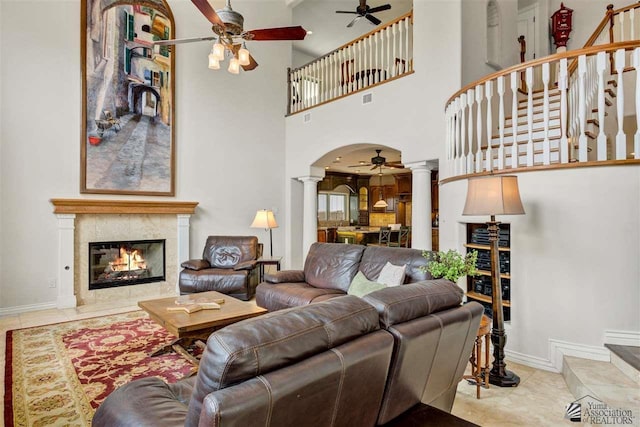 tiled living room with ornate columns, a high ceiling, and a tile fireplace