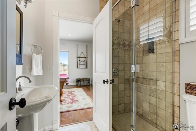 bathroom featuring hardwood / wood-style floors, an enclosed shower, and sink