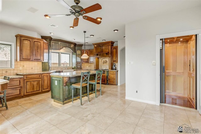 kitchen with a kitchen breakfast bar, backsplash, light stone counters, pendant lighting, and a center island