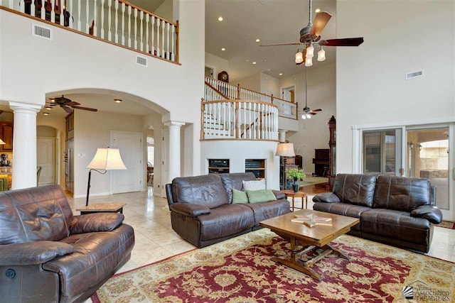 living room featuring light tile patterned floors, a high ceiling, and decorative columns