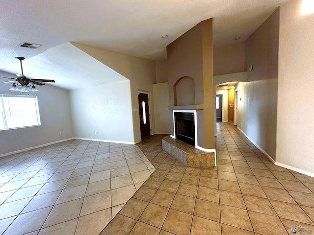 unfurnished living room with ceiling fan, a tile fireplace, and light tile patterned floors