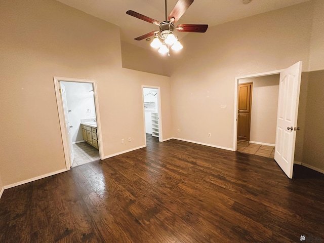 unfurnished bedroom with high vaulted ceiling, ensuite bath, ceiling fan, and dark hardwood / wood-style floors