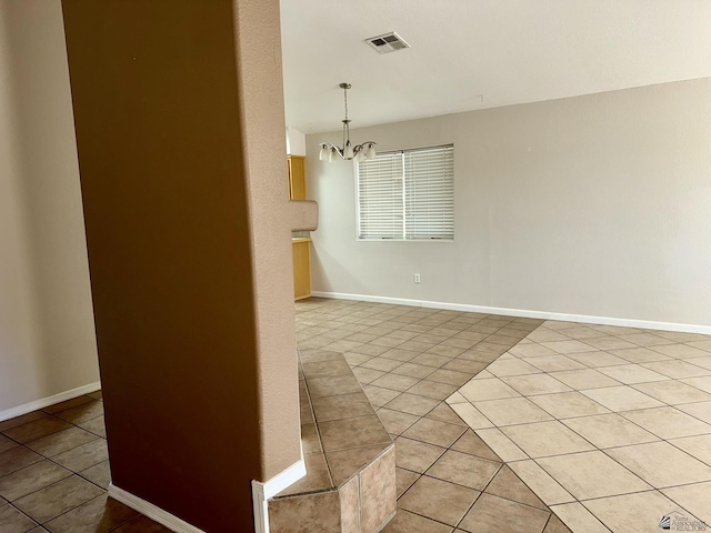 tiled spare room with a notable chandelier