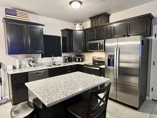 kitchen featuring a kitchen bar, light stone counters, stainless steel appliances, sink, and light tile patterned floors