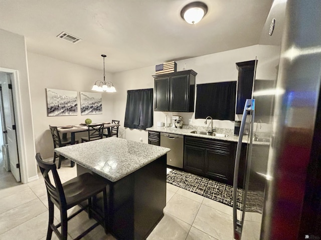 kitchen featuring stainless steel appliances, light tile patterned floors, pendant lighting, a notable chandelier, and a kitchen island