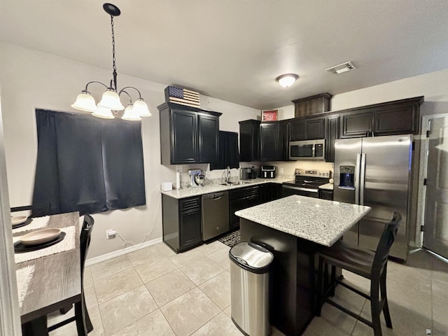 kitchen featuring light stone countertops, a center island, hanging light fixtures, stainless steel appliances, and an inviting chandelier