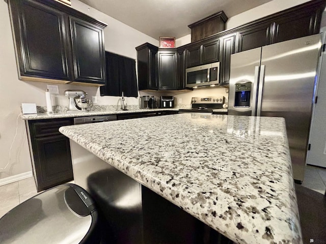 kitchen featuring light tile patterned floors, stainless steel appliances, light stone counters, and sink