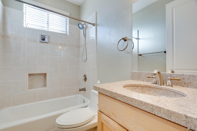 full bathroom featuring tiled shower / bath combo, vanity, and toilet