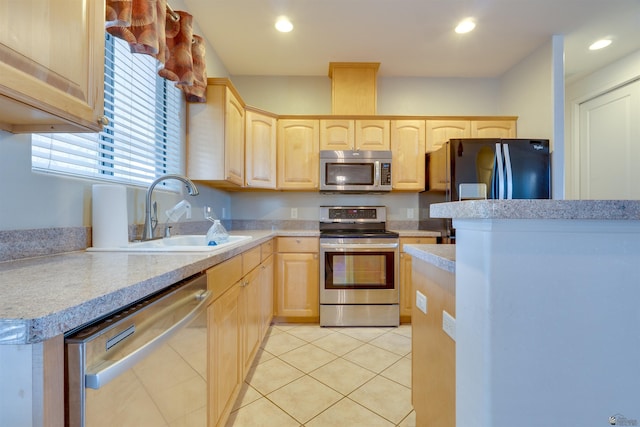 kitchen with light brown cabinetry, appliances with stainless steel finishes, light tile patterned floors, and sink