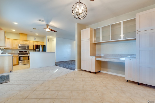 kitchen featuring stainless steel appliances, light brown cabinets, light tile patterned flooring, ceiling fan with notable chandelier, and hanging light fixtures