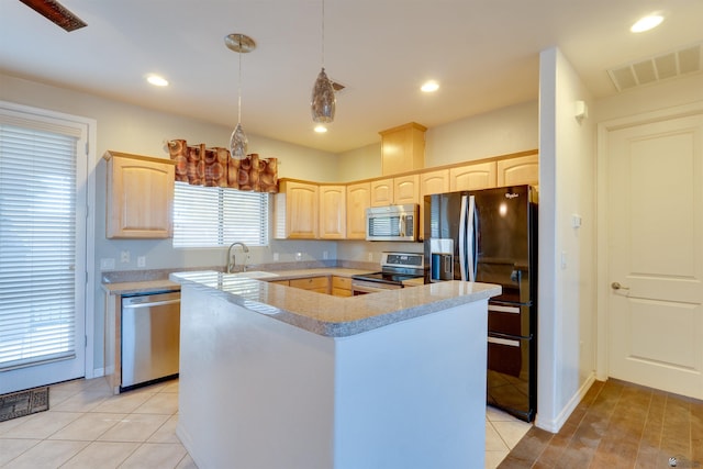 kitchen with hanging light fixtures, light tile patterned floors, a kitchen island, appliances with stainless steel finishes, and light brown cabinets