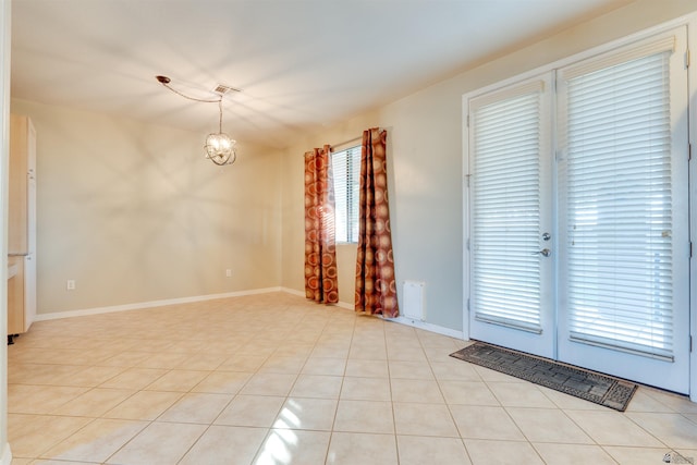 unfurnished room with a notable chandelier, a wealth of natural light, and light tile patterned floors