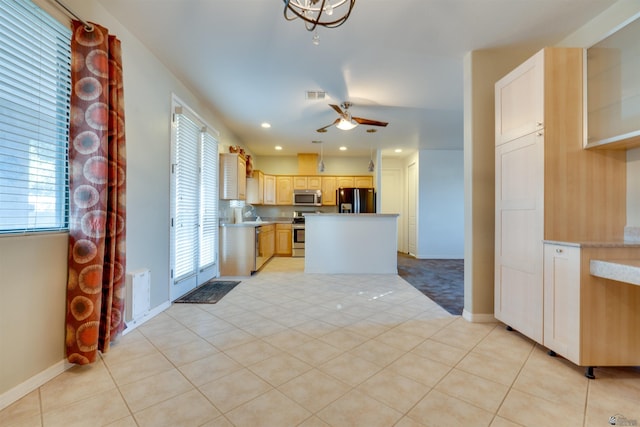 kitchen with light brown cabinets, ceiling fan, light tile patterned floors, a kitchen island, and appliances with stainless steel finishes